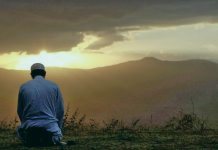 Мужчина совершает намаз в поле